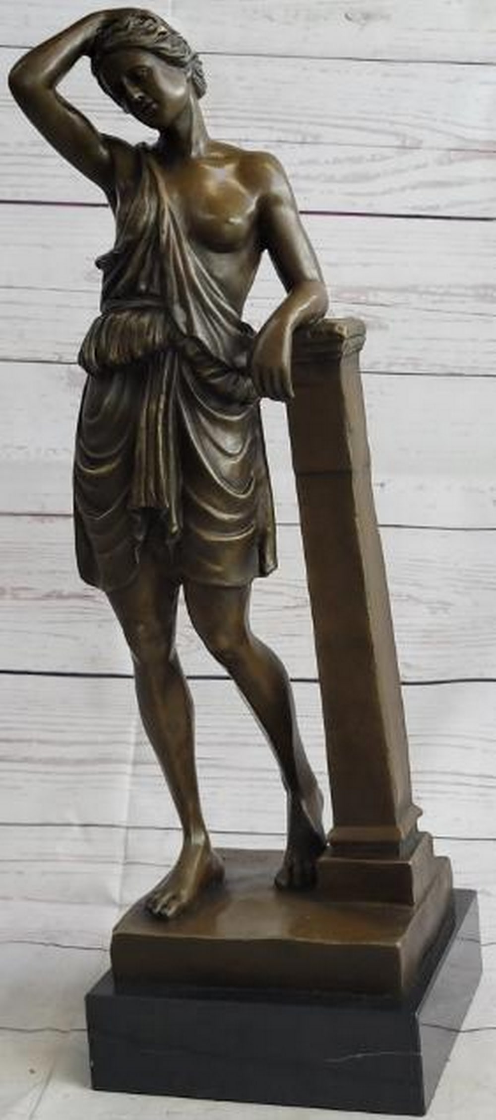 Goddess in Repose Bronze Sculpture: Goddess in Repose Bronze Sculpture This elegant reproduction bronze sculpture captures a semi-nude goddess in a moment of relaxed grace, leaning thoughtfully against a classical pillar. Her elbow rest