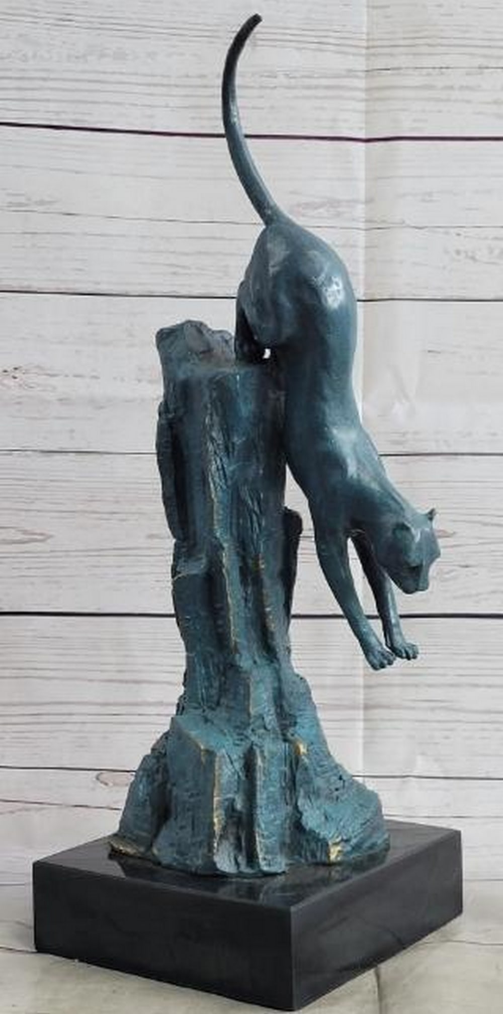 Blue Patina Bronze Cougar Sculpture: Blue Patina Bronze Cougar Sculpture Captured in a breathtaking display of motion and power, this bronze sculpture features a cougar mid-pounce, its body fully stretched as it launches downward from th