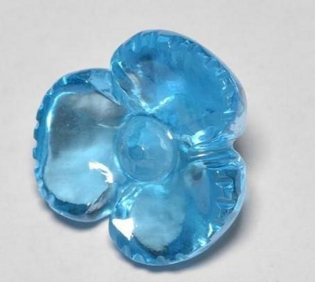 Swiss Blue Topaz Carved Flower Gemstone: Swiss Blue Topaz Carved Flower Gemstone Brilliant and refreshing, this loose gemstone is expertly carved into a delicate flower from radiant Swiss Blue topaz. The vivid sky-blue hue sparkles with clar