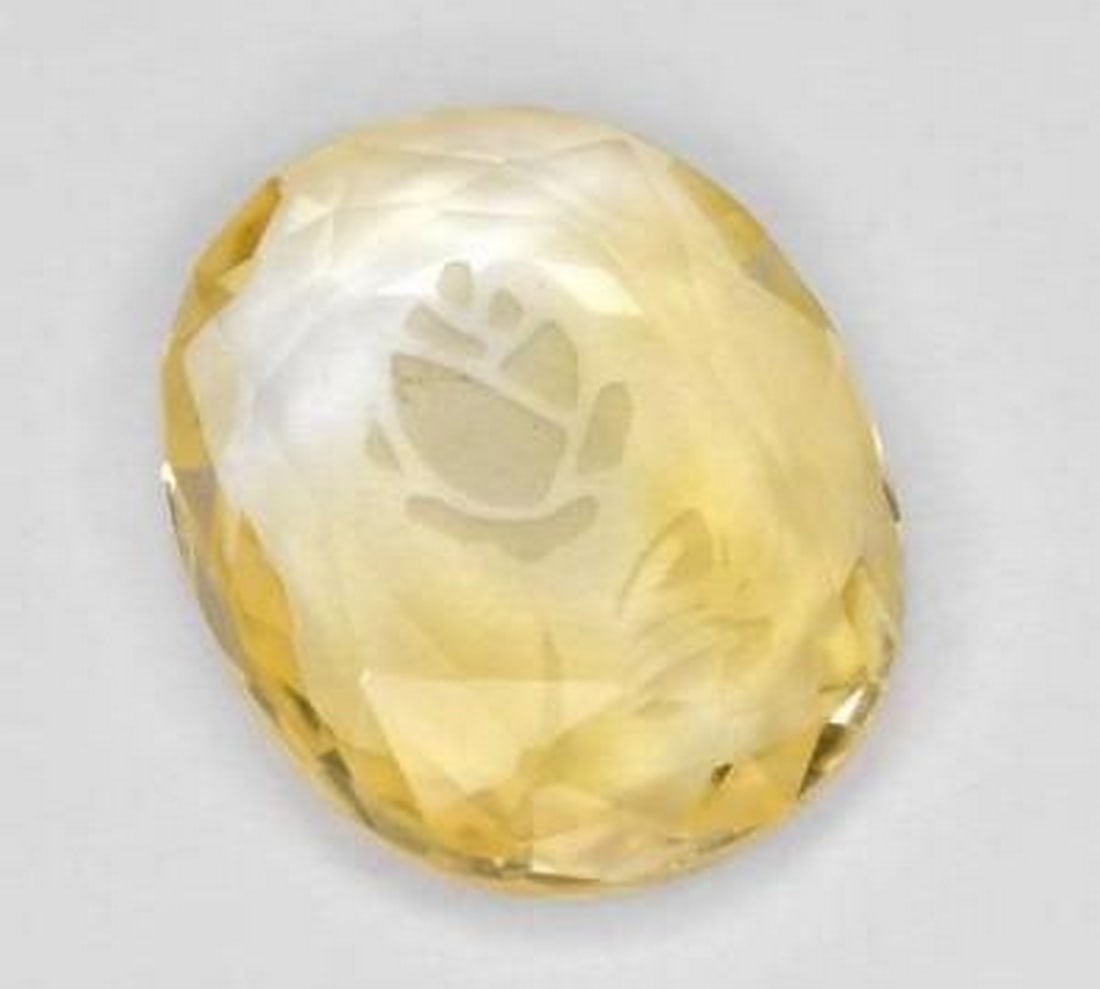 Bright Gold Citrine Oval Gemstone with Etched Flower Detail: Bright Gold Citrine Oval Gemstone with Etched Flower Detail Radiating warmth and brilliance, this loose citrine gemstone is carved into an elegant oval and features a delicate flower etched into its s