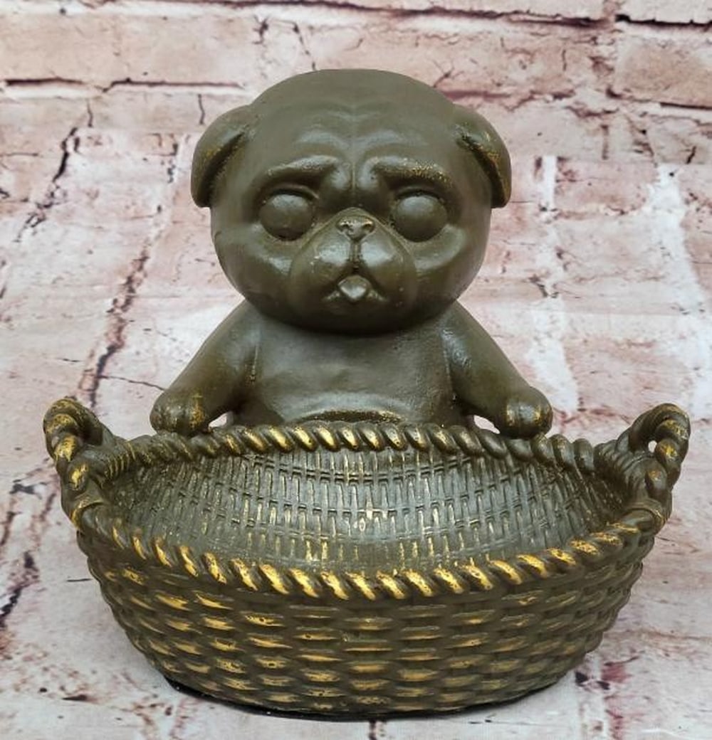 Bronze Pug with Basket Sculpture: Bronze Pug with Basket Sculpture Full of charm and character, this bronze sculpture bearing the signature of artist M. Lopez (Milo), features a delightful pug sitting upright with its tongue playfully
