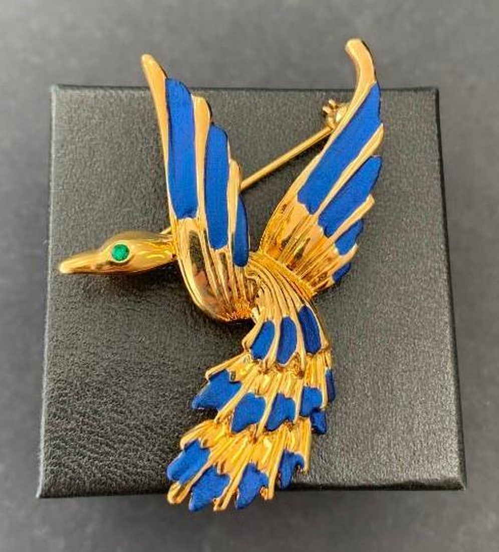 Vintage Enamel Bird Brooch with Gemstone Eye: Vintage Enamel Bird Brooch with Gemstone Eye This exquisite vintage brooch features a stylized bird crafted in gold-toned metal, adorned with vibrant blue enamel detailing on its wings and tail. A str