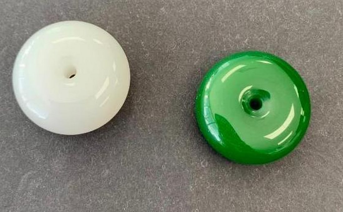 Jade Beads with Polished Finish: Jade Beads with Polished Finish A pair of elegant round beads featuring a smooth, glossy surface and central hole—ideal for stringing or crafting. One bead is a classic white, while the other showca