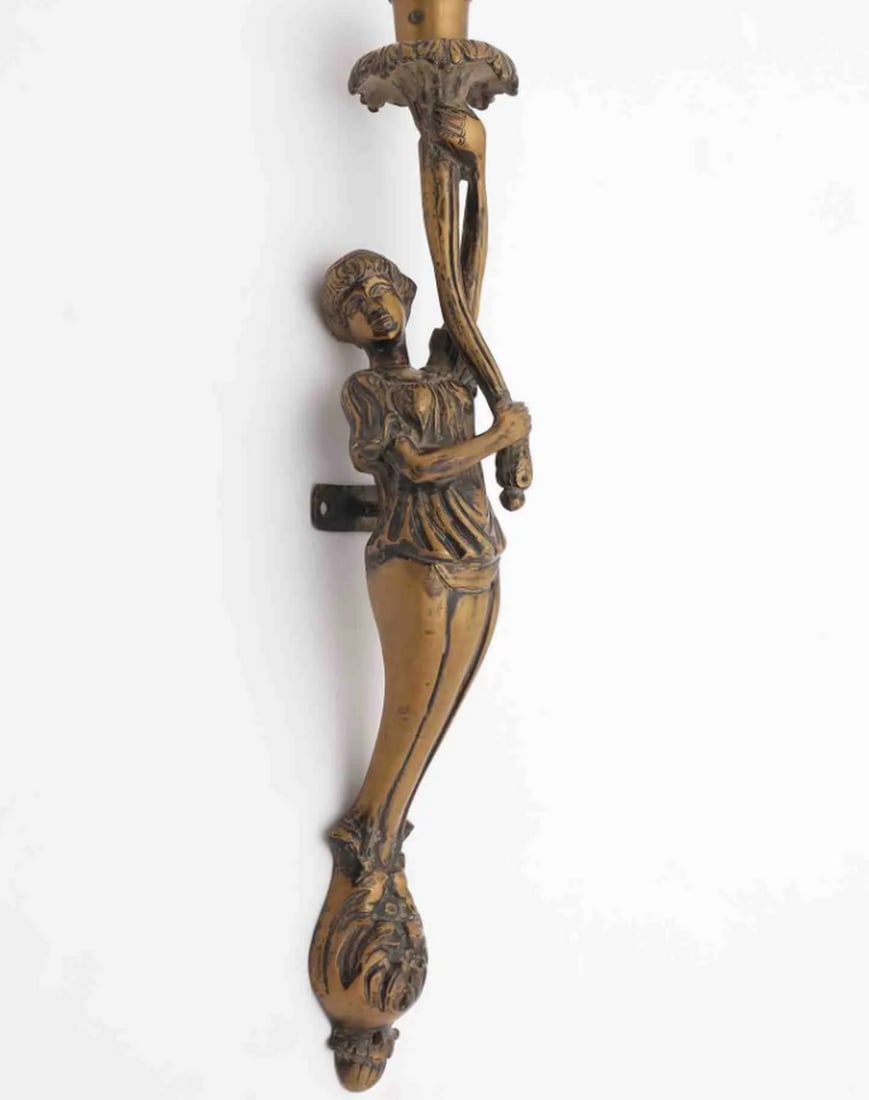 18" Brass Lady Torch Wall Sconce Candle Holder: 18" Brass Lady Torch Wall Sconce Candle Holder Wall-mounted candle holder crafted from brass, depicting a female figure holding a torch-shaped candle stand. The sculpture combines decorative artis