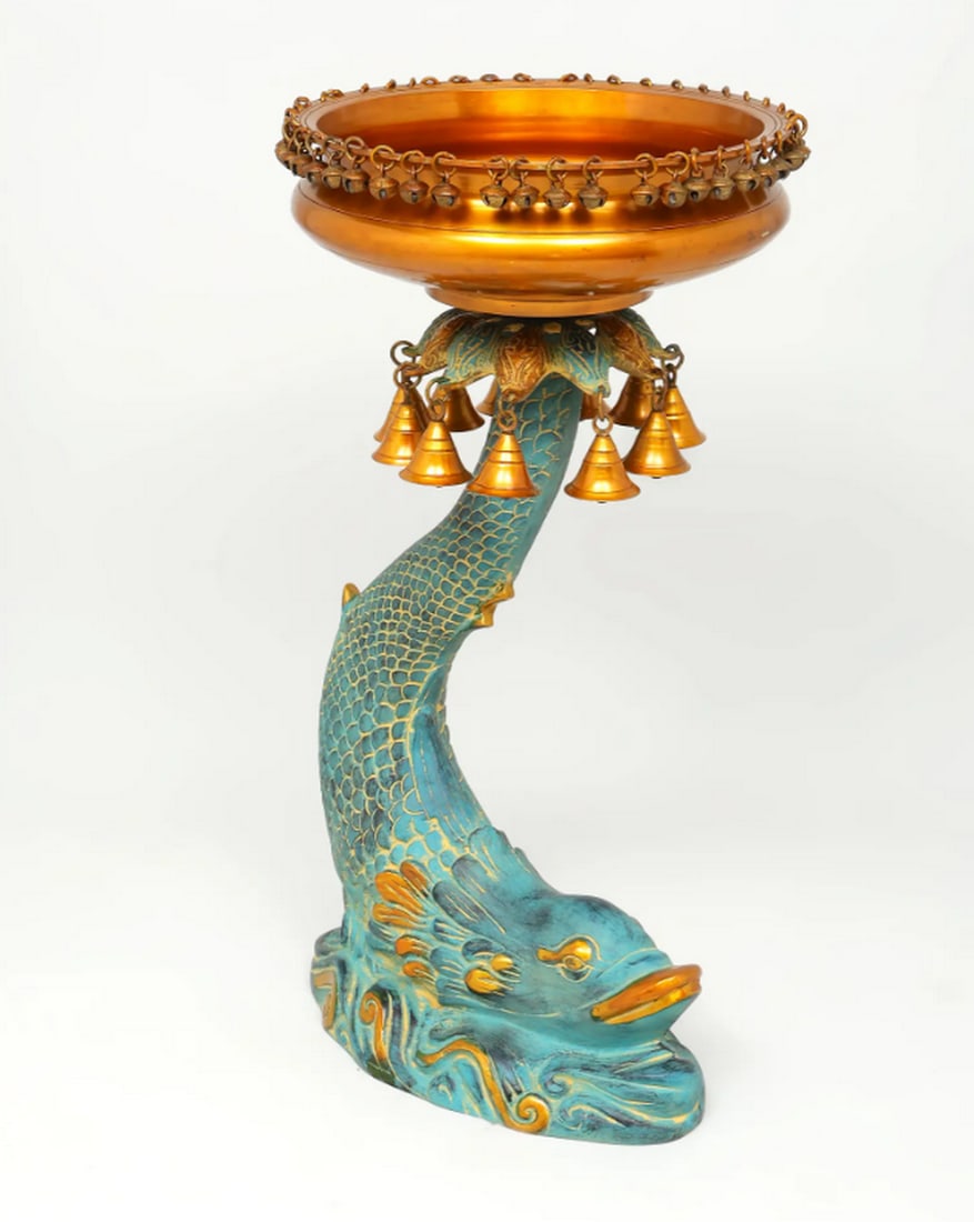 24.5" Urli Bowl on Koi Yama Carp Stand with Bells and Ghungroos: 24.5" Urli Bowl on Koi Yama Carp Stand with Bells and Ghungroos Crafted from solid brass, this Urli rests on a carved Koi Yama Carp stand. The fish is detailed with scaled patterns and a blooming 