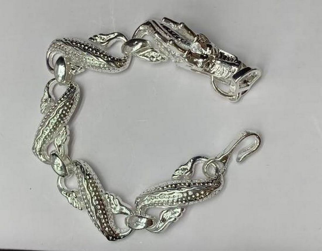 Tibetan Silver Toned Flying Dragon Bracelet: A Tibetan Silver Toned Flying Dragon Bracelet. This striking piece of jewelry embodies both power and elegance. The bracelet is designed with intricate detail, where the body and head of a majestic