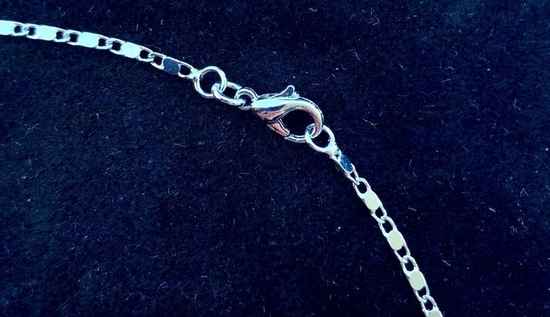 Silver-Toned Necklace with Iridescent Dark Pearl Pendant: Silver-Toned Necklace with Iridescent Dark Pearl Pendant A striking silver-toned necklace featuring a dark, iridescent pearl pendant that subtly shifts colors in the light. The pearl is elegantly fram