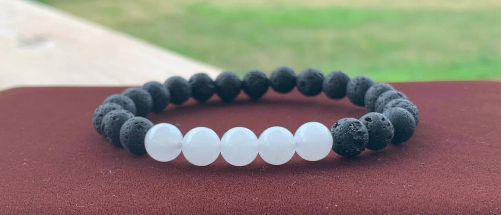 Earthbound Harmony Bracelet: Earthbound Harmony Bracelet A harmonious blend of earth and tranquility, this beaded bracelet pairs creamy milky jade with raw black lava stones for a striking contrast in texture and tone. The jade b