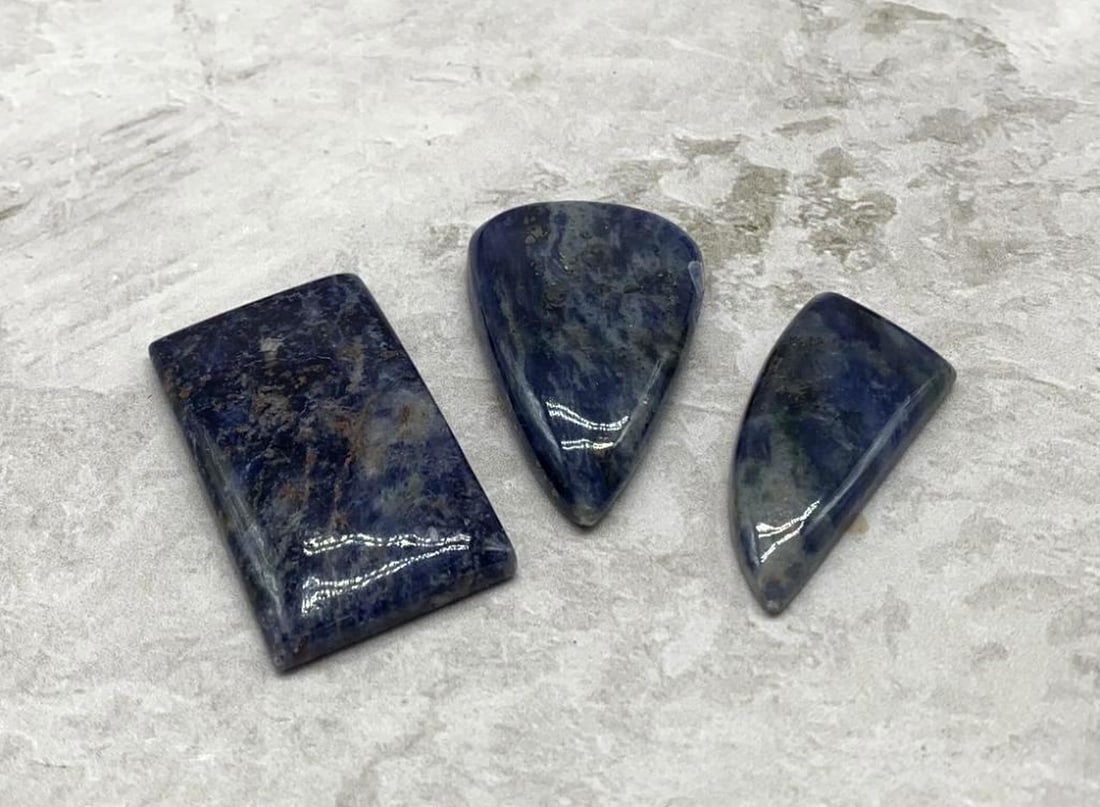 135ct Lot of 3 Blue Sodalite Stones: 135ct Lot of 3 Blue Sodalite Stones This striking 135-carat lot features three richly patterned blue sodalite stones, each showcasing a unique interplay of deep indigo, royal blue, and snowy white vei