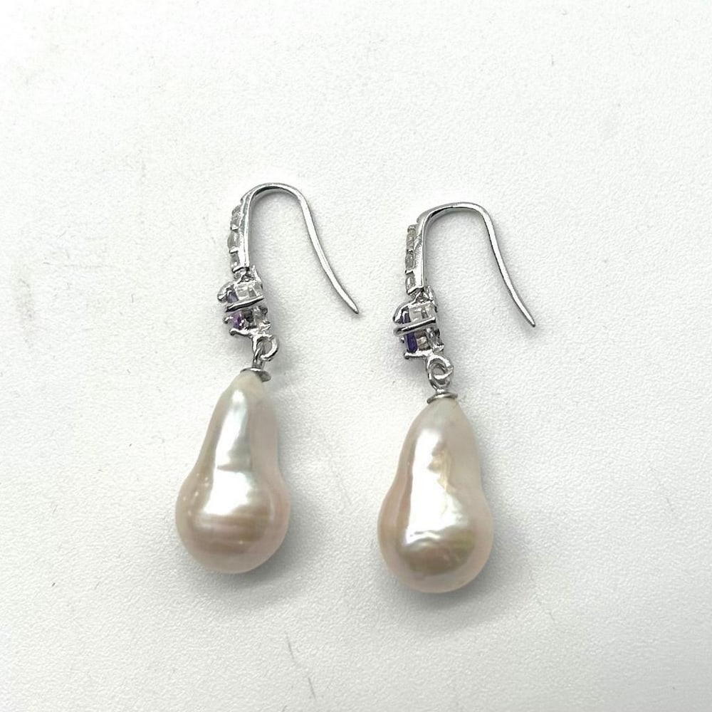 White Pearl And Amethyst Stone Earring: White Pearl And Amethyst Stone Earring These earrings are an exquisite and elegant accessory that combines the beauty of three gemstones in a stunning design; Pearls, Amethyst, and Cubic Zirconia. The