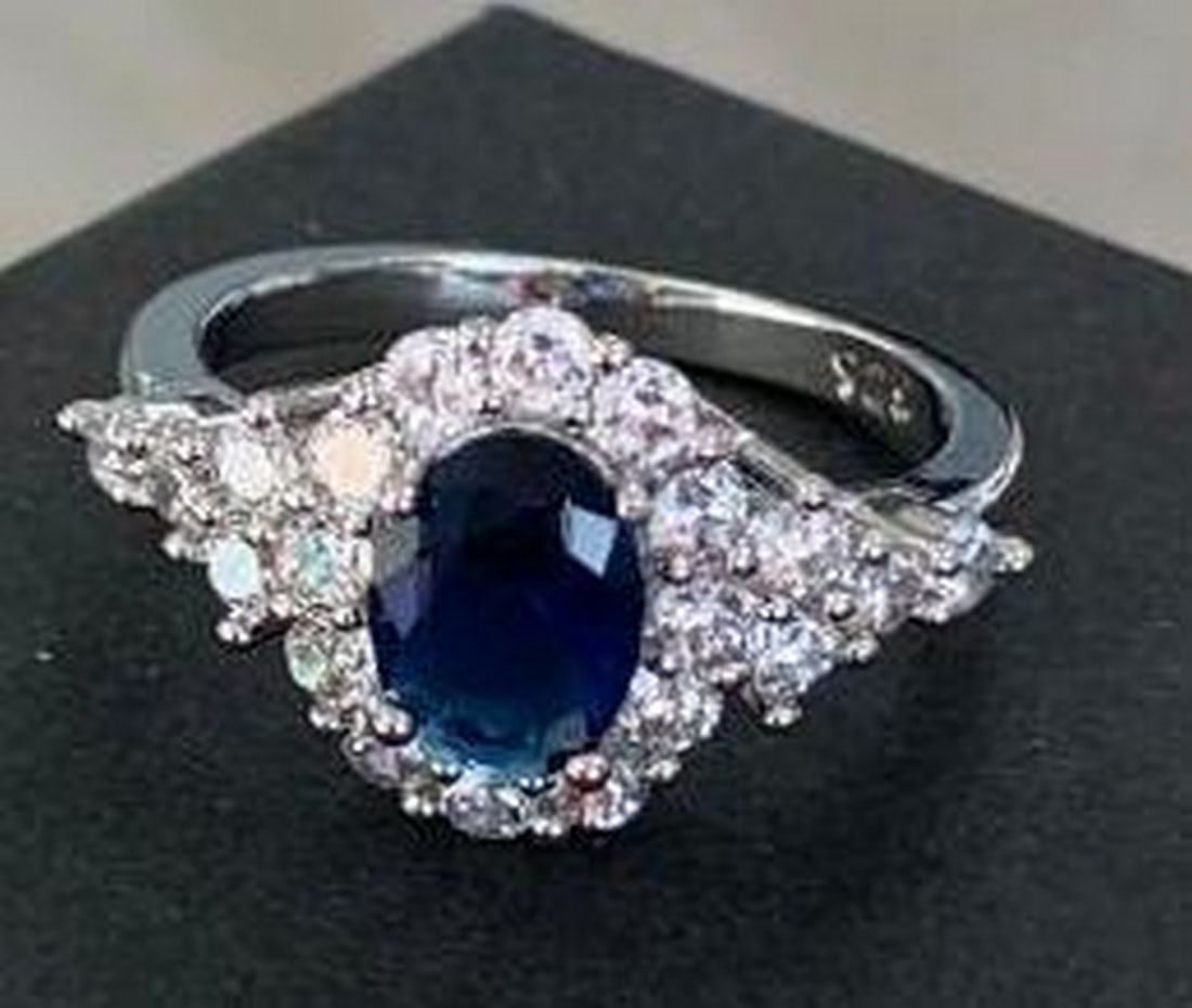 Sterling Silver Ring with Blue Center Stone & Crystal Halo: Sterling Silver Ring with Blue Center Stone & Crystal Halo A striking blend of elegance and sparkle. This sterling silver ring features a brilliant blue stone at its center, encircled by a halo