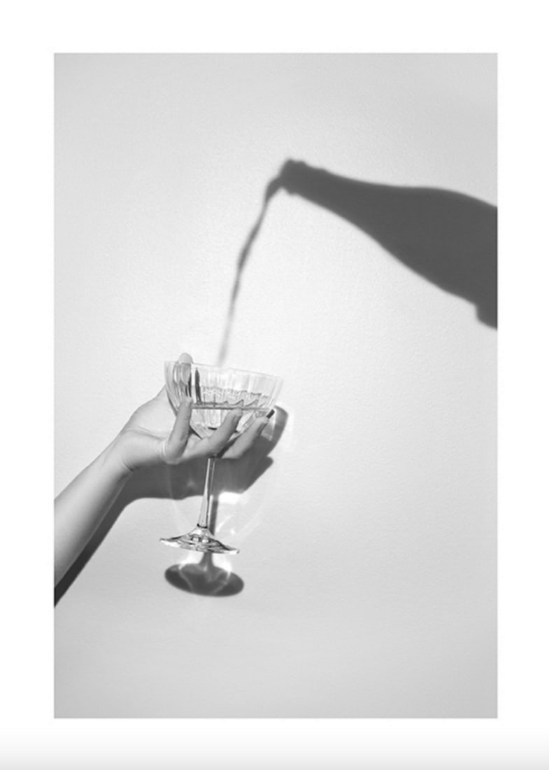 Black & White Champagne Pouring Poster Print: Black & White Champagne Pouring Poster Print Grey photograph of a shadow of a champagne bottle and a hand holding a champagne glass. Photograph in grey-scale of a hand holding a champagne glass an