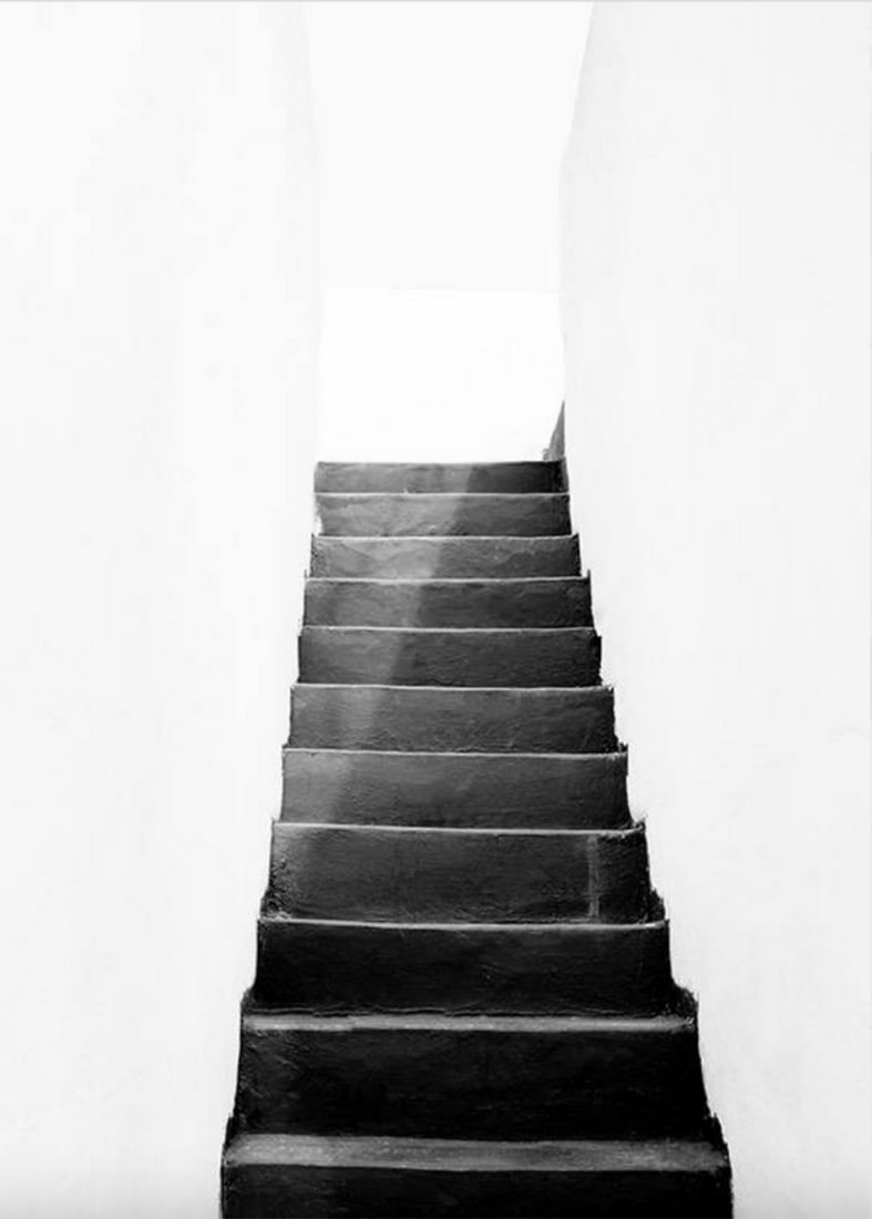 Black & White Stairs Poster Print: Black & White Stairs Poster Print Photograph of a dark stairway with white walls surrounding. Dark stairs photographed from the bottom surrounded by white walls leading up to a bright place.