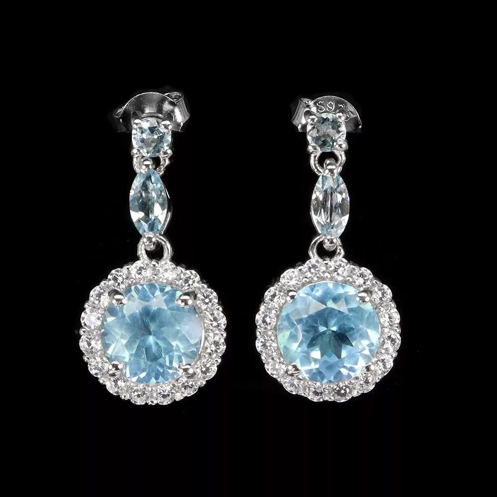 Round Sky Blue Topaz Earrings in 925 Sterling Silver: Round Sky Blue Topaz Earrings in 925 Sterling Silver These elegant earrings feature heated round sky blue topaz gemstones, each 8mm in size, set in 925 sterling silver. The serene sky blue topaz exude