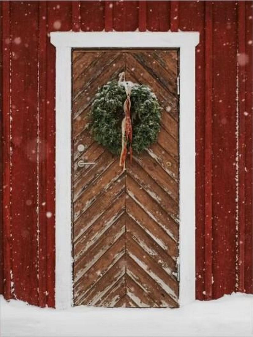 Winter Wreath Door Canvas Print: Winter Wreath Door Canvas Print An artwork showing a festive wooden door with a wreath on a red wall, surrounded by falling snow. The composition captures a cozy winter scene with a subtle grainy text