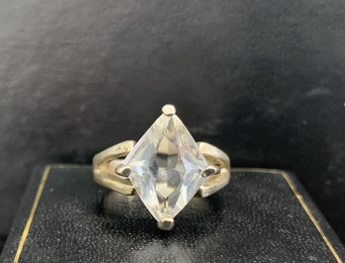 Silver-Tone Ring with Large Diamond-Shaped Clear Stone: Silver-Tone Ring with Large Diamond-Shaped Clear Stone Make a bold statement with this elegant silver-toned ring, featuring a large diamond-shaped clear stone as its centerpiece. The bright, faceted