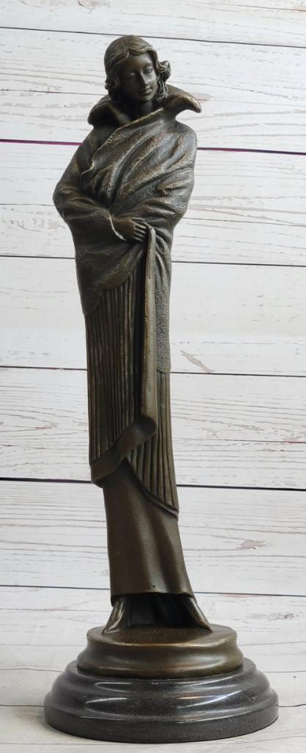 Art Deco Young Woman in Long Jacket Bronze Sculpture – 16" x 5": Art Deco Young Woman in Long Jacket Bronze Sculpture – 16" x 5" A graceful Art Deco bronze sculpture of a young woman wrapped in a long flowing jacket, her gaze turned downward as if