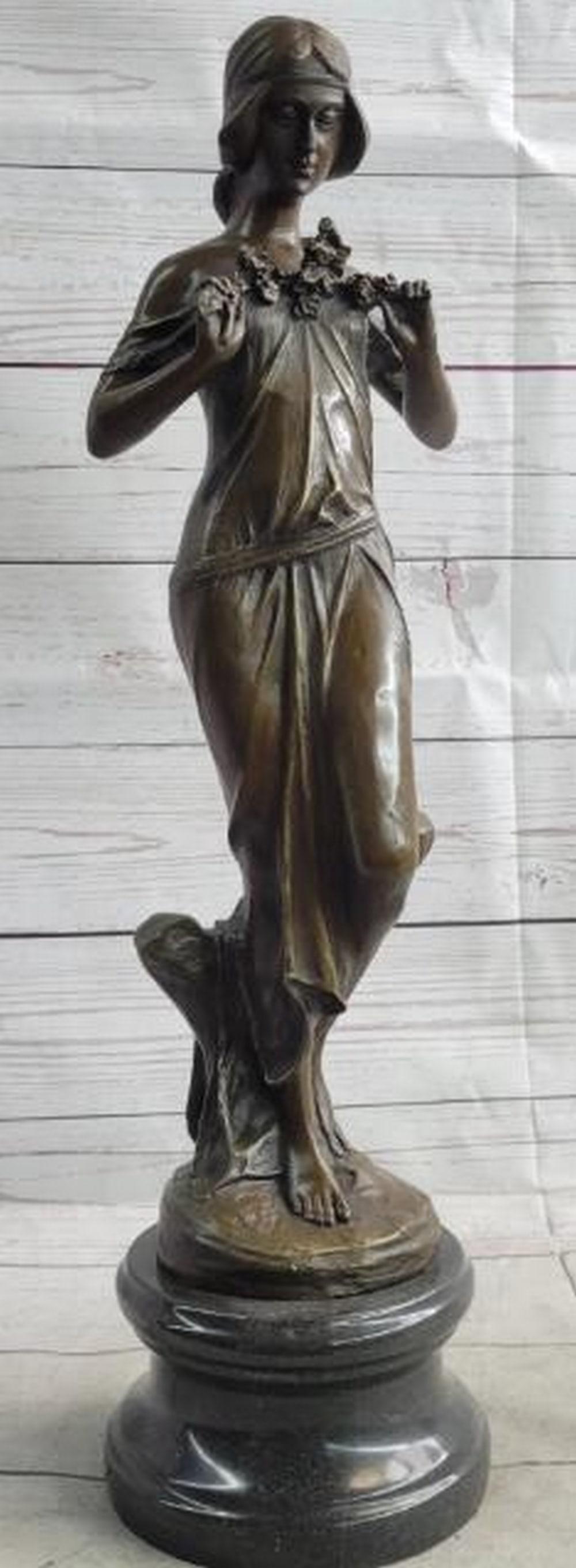 Embrace of Spring Bronze Sculpture - 19.5" x 5.5": Embrace of Spring Bronze Sculpture - 19.5" x 5.5". A bronze sculpture, inspired by and bearing the signature of renowned artist Jean Patoue, of a woman gently holding flowers to her chest, sym
