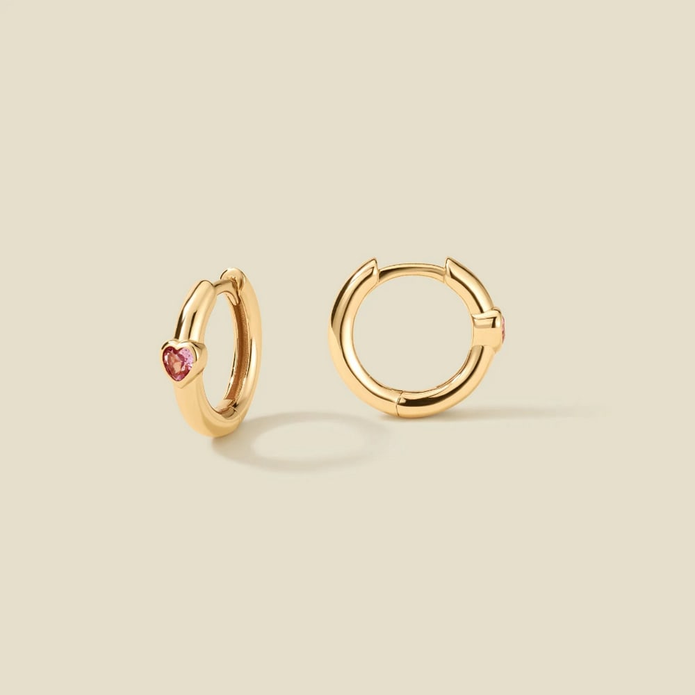 Vermeil Gold & Heart Shaped Pink CZ Huggie Hoop Earrings: Vermeil Gold & Heart Shaped Pink CZ Huggie Hoop Earrings Embrace effortless romance with these gold huggie hoops, adorned with dreamy pink CZ hearts and a secure hinge closure. A timeless blend