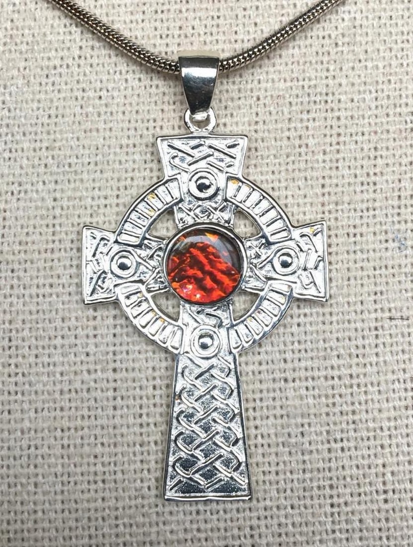 Crimson Cross Ammolite Pendant: Crimson Cross Ammolite Pendant This ammolite cross pendant is crafted in sterling silver, featuring a 6mm red quartz-capped triplet. The sturdy setting makes it a versatile piece that would suit both