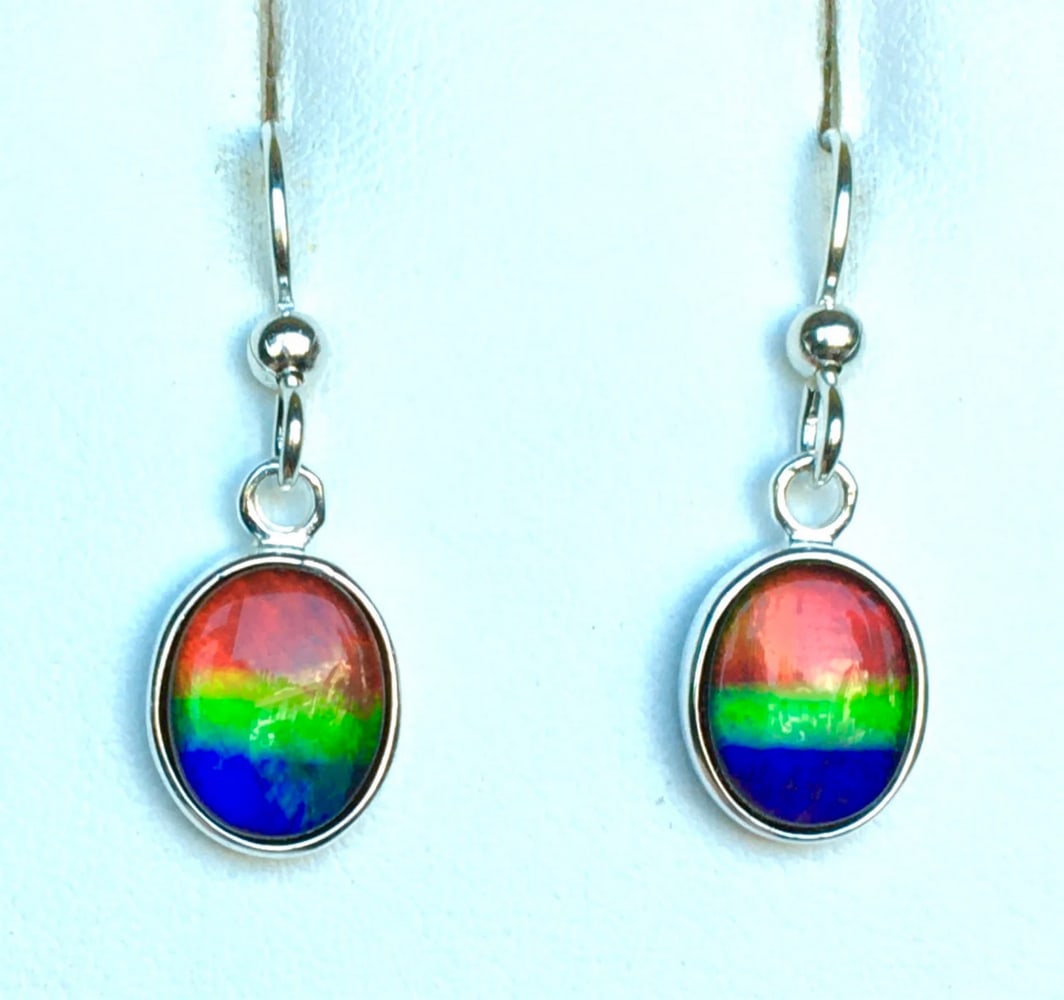 Multi-colour Ammolite Earrings: Multi-colour Ammolite Earrings These Ammolite earrings feature vibrant multicolored gemstones, each measuring 10mm x 8mm with a low-dome quartz cap. Set in sterling silver, they hang from matching ste