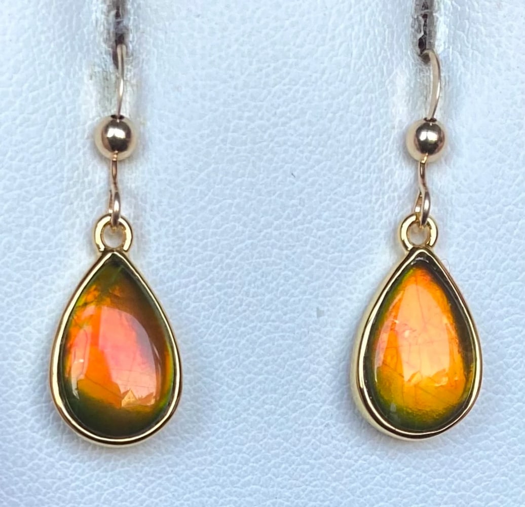 Teardrop Orange Ammolite Earrings: Teardrop Orange Ammolite Earrings These teardrop-shaped Ammolite earrings feature 12mm x 8mm low-dome quartz-capped triplets. Set in gold-plated (vermeil) sterling silver, they hang from gold-filled (
