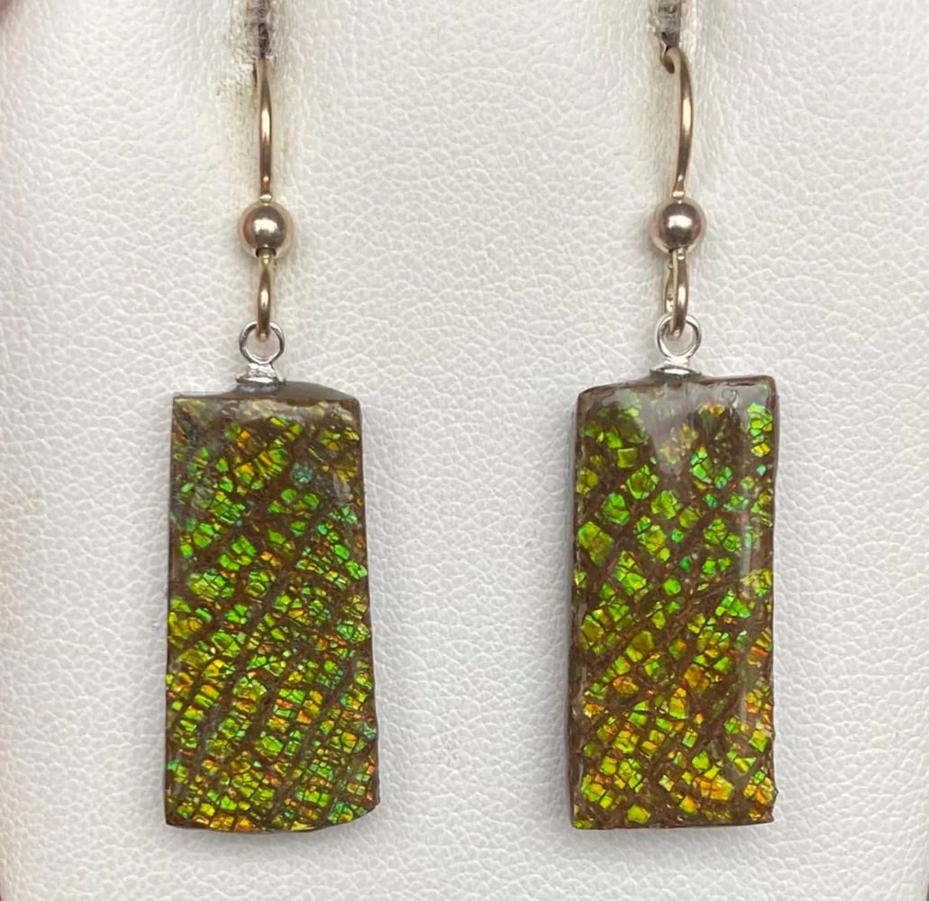 Green Dragon skin Ammolite Earrings: Green Dragon skin Ammolite Earrings This pair of earthy Ammolite earrings features gemstones averaging 23mm x 11mm with a delicate coating. Suspended from sterling silver pins and ear wires, they