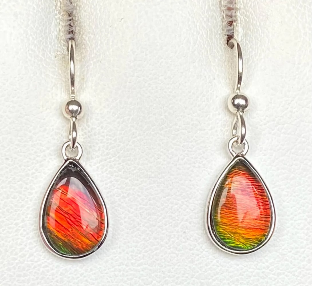 Reddish Orange Ammolite Earrings: Reddish Orange Ammolite Earrings These teardrop-shaped Ammolite earrings feature 12mm x 8mm low-dome quartz-capped triplets. Set in sterling silver with an anti-tarnish rhodium finish, they hang from 