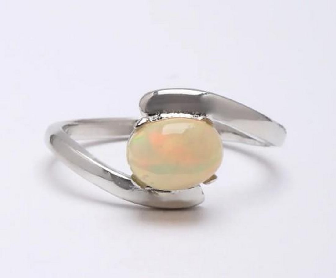 Iridescent Whisper: Iridescent Whisper - Oval Ethiopian Opal Ring Discover the enchanting allure of Ethiopian Opal with this exquisitely crafted ring. Known for its mesmerizing play-of-color, the opal radiates a gentle,