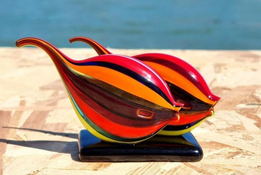 Tropical Duo: Tropical Duo Bursting with color and life, this Murano glass sculpture features two tropical fish gracefully poised on a clear base. Handcrafted with meticulous attention to detail, each fish