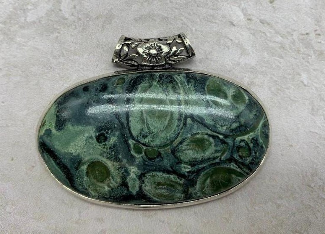 Silver-Plated Chunky Pendant Marbled Blue, Green & Black with Floral Detailing: Silver-Plated Chunky Pendant Marbled Blue, Green & Black with Floral Detailing This stunning African Kambaba Jasper pendant combines natural beauty with intricate craftsmanship. The bold, marbled hues