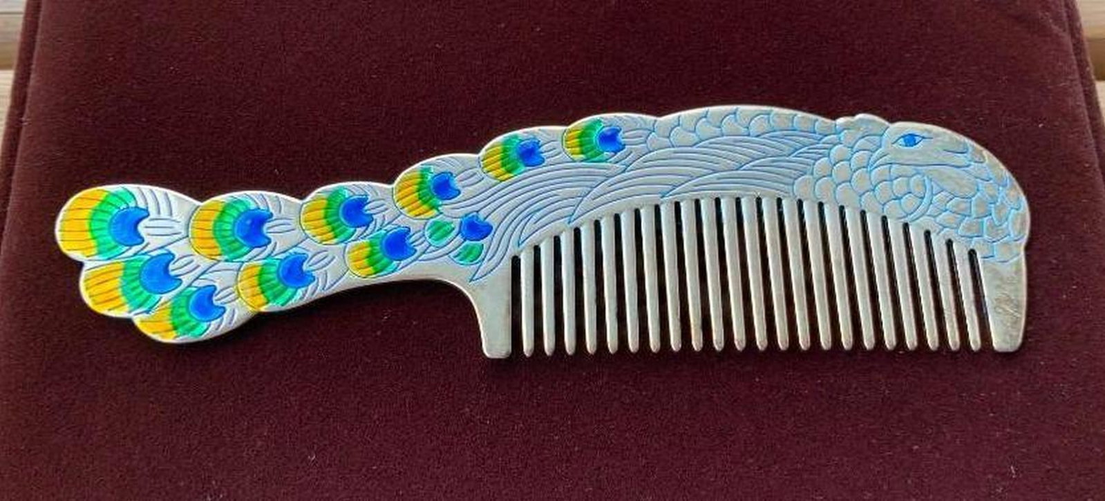 Silver-Colored Comb with Intricate Peacock Design: Silver-Colored Comb with Intricate Peacock Design Add a touch of elegance to your grooming routine with this beautifully designed silver-colored comb. The handle and top feature a detailed peacock