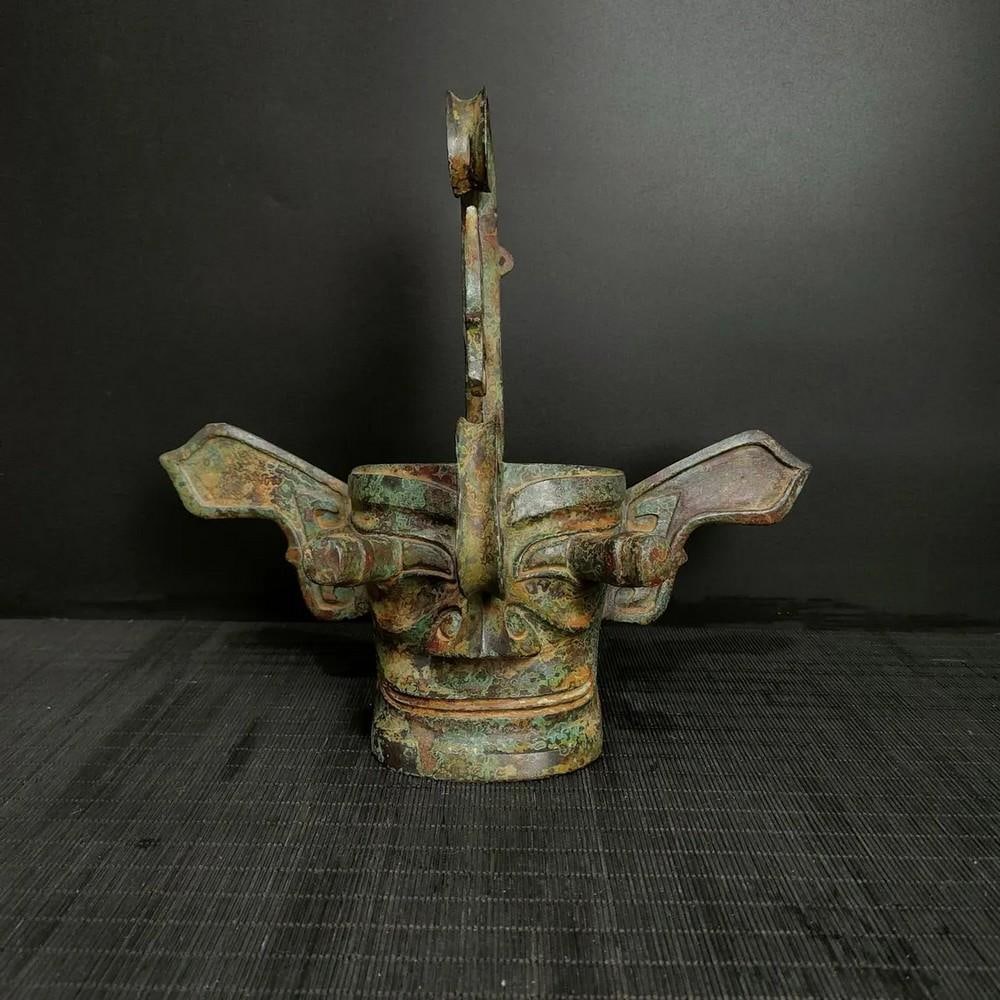 Antique Chinese Sanxingdui Giant Bronze Face Mask: Antique Chinese Sanxingdui Giant Bronze Face Mask This antique Chinese Sanxingdui giant bronze face mask is a striking representation of ancient artistry and mystique. The bold, exaggerated features a
