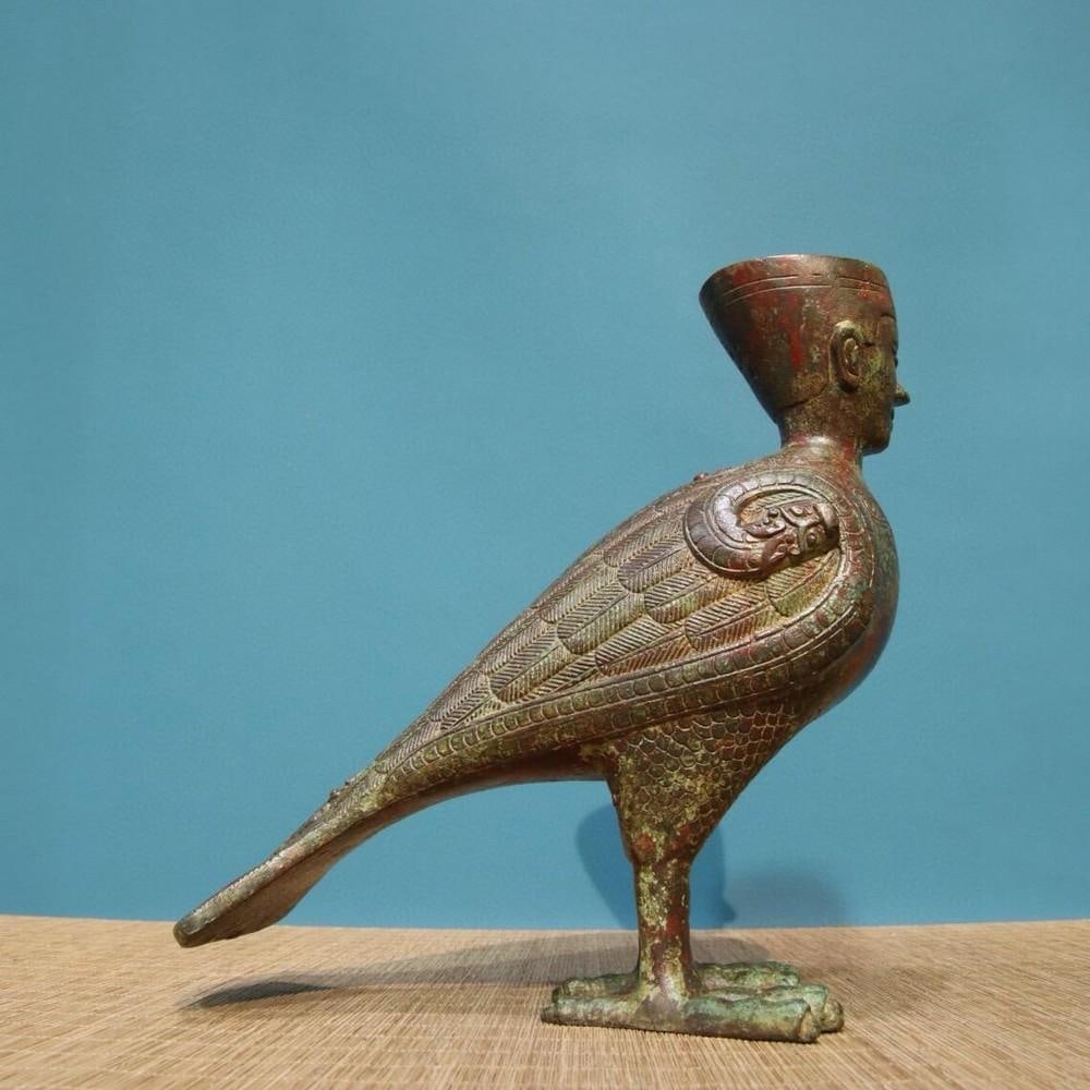Bronze Human-Face Bird Statue: Bronze Human-Face Bird Statue This rare antique statue depicts a mystical human-faced bird, intricately crafted in bronze with fine inscriptions. A testament to traditional Chinese artistry, its hand-