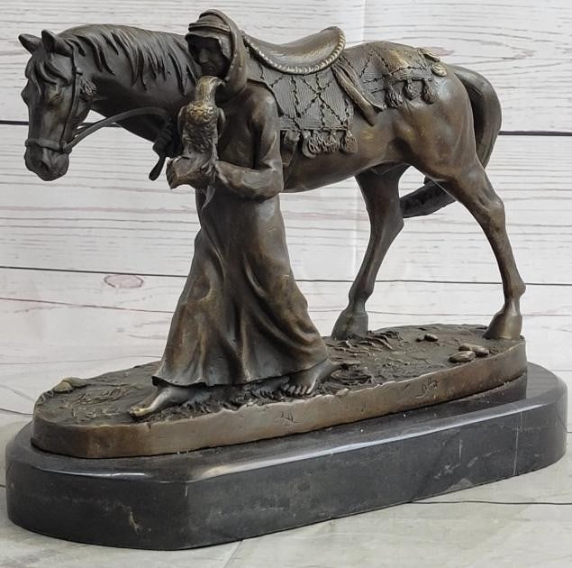 Man with Falcon and Horse Bronze Sculpture: Man with Falcon and Horse Bronze Sculpture This striking bronze sculpture captures a moment of quiet strength and harmony between man, animal, and tradition. A robed man holds a falcon confidently on 