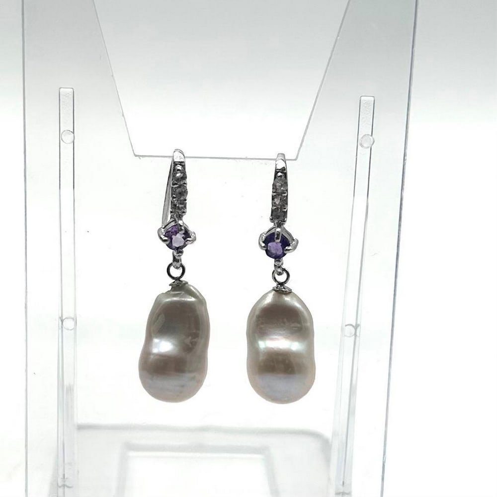 White Pearl And Amethyst Stone Earring: White Pearl And Amethyst Stone Earring These earrings are an exquisite and elegant accessory that combines the beauty of three gemstones in a stunning design; Pearls, Amethyst, and Cubic Zirconia.