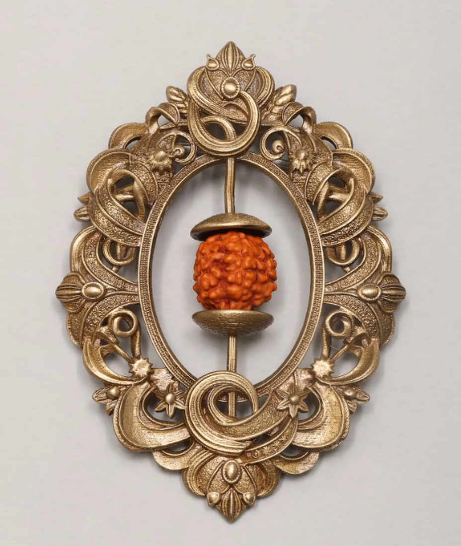 Sacred Rudraksha Floral Brooch: Sacred Rudraksha Floral Brooch Adorn your attire with this beautifully crafted brooch, featuring a calming Rudraksha bead encased in an intricate brass floral frame. The ornate design blends