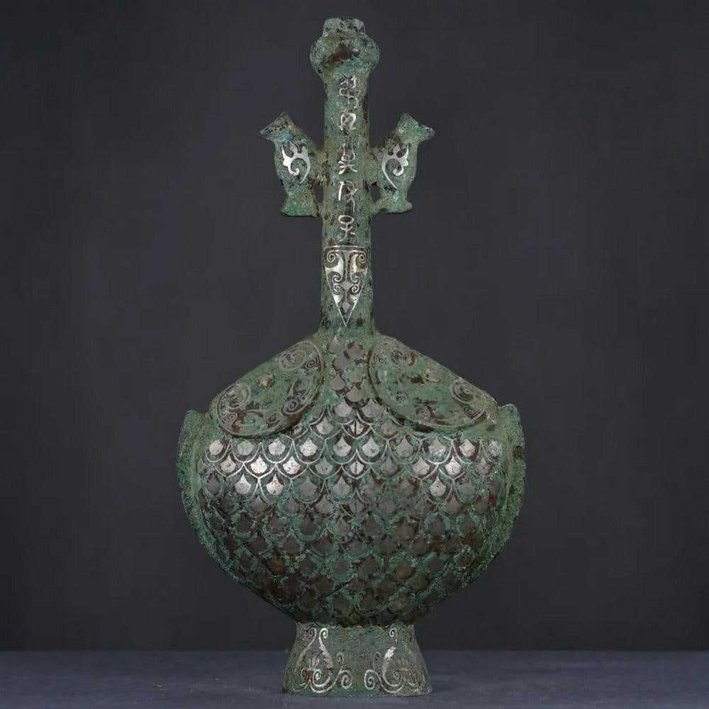 Antique Bronze Flat Pot with Silver Inlay Statue: Antique Bronze Flat Pot with Silver Inlay Statue This exquisite Chinese antique features a hand-crafted bronze flat pot, delicately inlaid with silver accents. The sleek design and intricate detailing