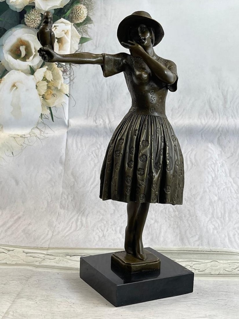 Beautiful Woman Holding a Bird on her Outstretched Arm Bronze Sculpture: Beautiful Woman Holding a Bird on her Outstretched Arm Bronze Sculpture The delightful young woman is dressed in a classy and feminine sundress. Her chic sunhat rests on her head with her bob peeking 