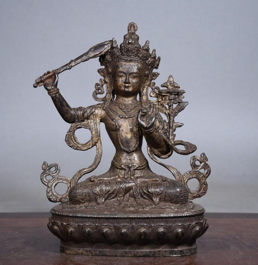 Gilded Copper Sword-Holding Manjusri Buddha Statue: Gilded Copper Sword-Holding Manjusri Buddha Statue This antique Manjusri Buddha statue is a stunning example of traditional Chinese craftsmanship, meticulously handcrafted from pure copper and enhance