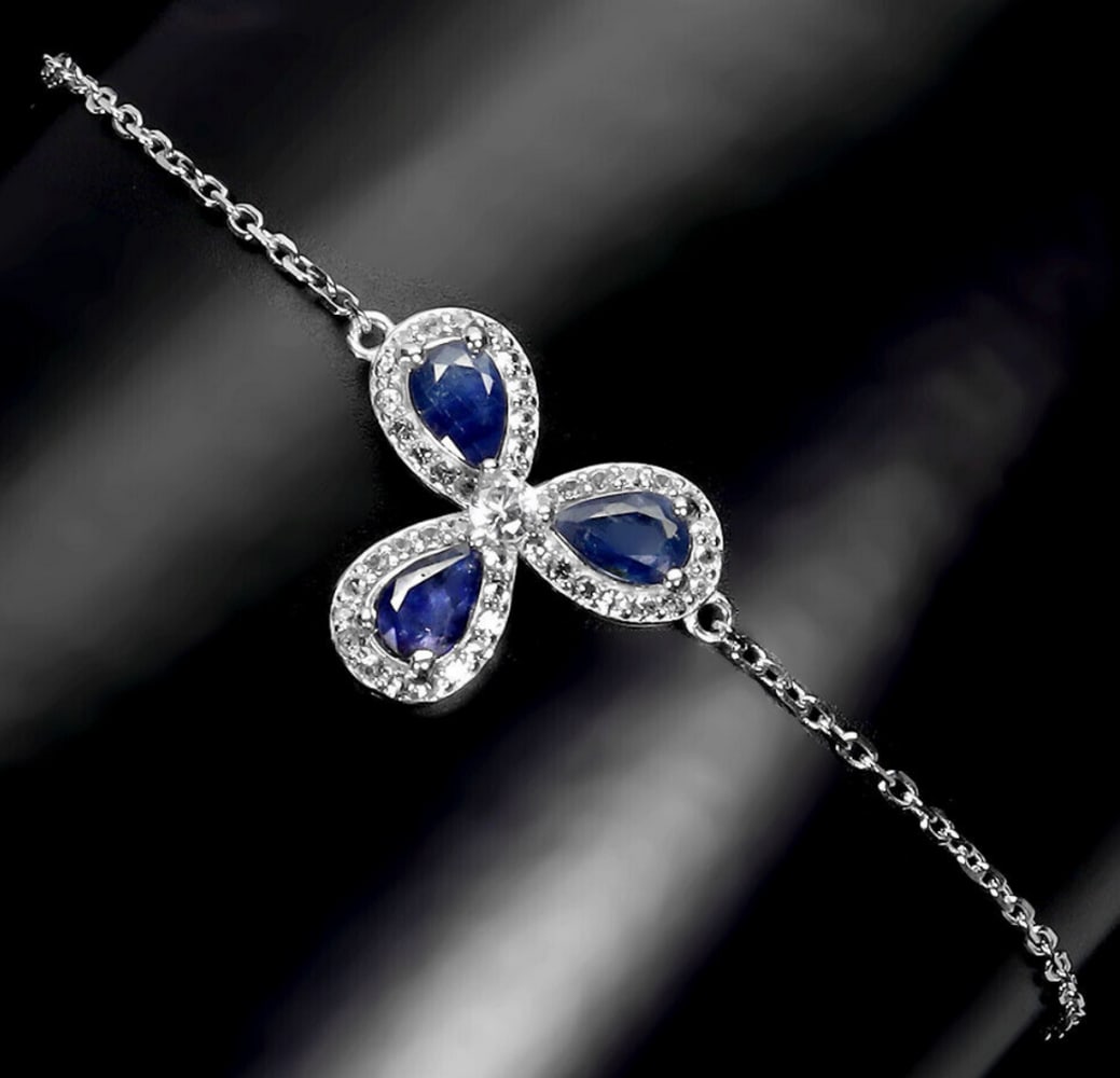 Rich Blue Sapphire and White Topaz Petal Bracelet: Rich Blue Sapphire and White Topaz Petal Bracelet This exquisite bracelet features a cascade of three petal-like pear-shaped blue sapphire gemstones, arranged in a floral-inspired design. Each