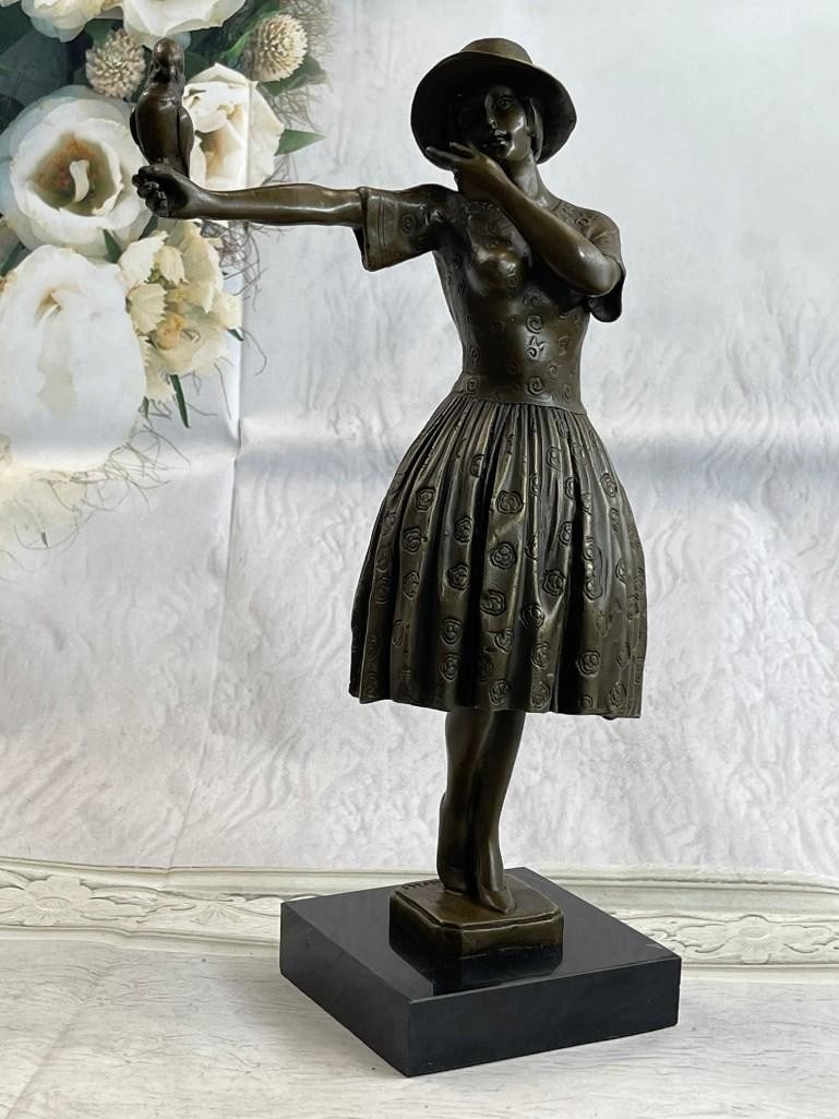 Elegant Young Lady Holding a Bird on her Outstretched Arm Bronze Statue: Elegant Young Lady Holding a Bird on her Outstretched Arm Bronze Statue. The delightful young woman is dressed in a classy and feminine sundress. Her chic sunhat rests on her head with her bob peeking