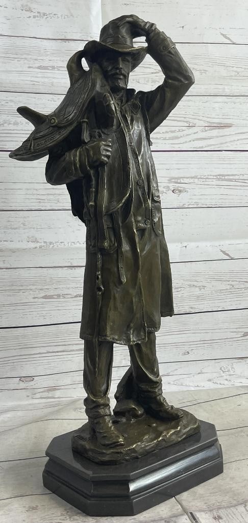Country Western Cowboy Hauling Saddle Bronze Sculpture Statue Art Decor: This is a sculpture of a classic cowboy. He wears his cowboy hat and his trench coat. On his feet her wears boots which his jeans cover in between his legs is a bunch of twigs that were gathered for f