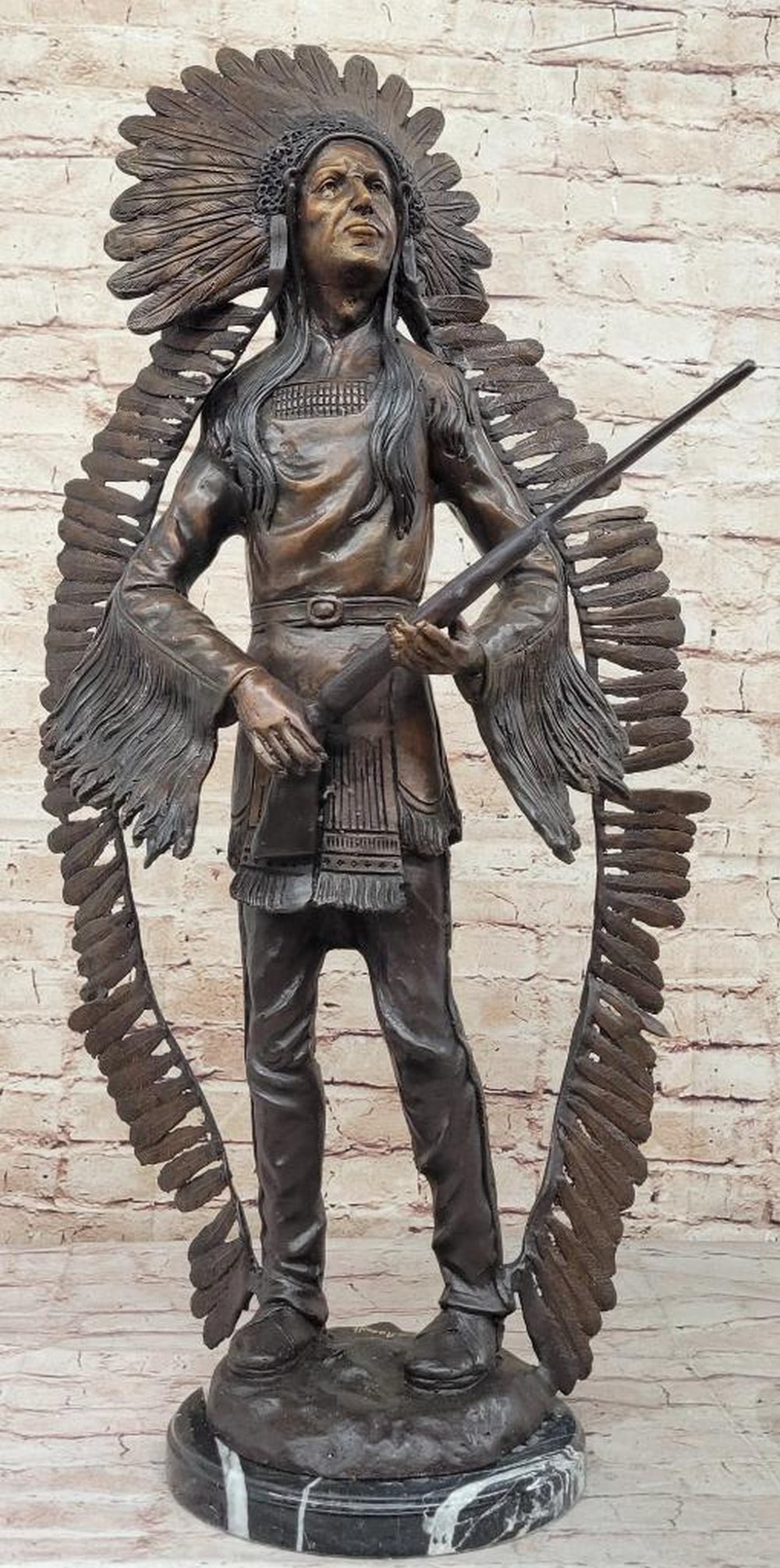Native American Holding Rifle Inspired Bronze Statue - 30'' x 16'': Native American Holding Rifle Inspired Bronze Statue - 30" x 16" This bronze statue depicts a Native American figure standing upright, holding a rifle in both hands. The intricate detailing of