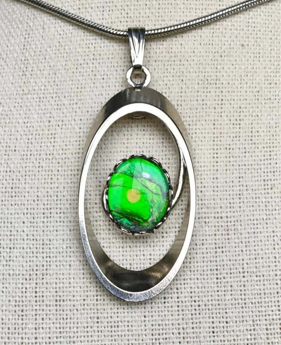 Pastel Hues Ammolite Pendant: Pastel Hues Ammolite Pendant This ammolite pendant features a 12mm x 10mm low dome triplet in green, with a small inclusion visible in the third photo. This natural characteristic is to be expected, a