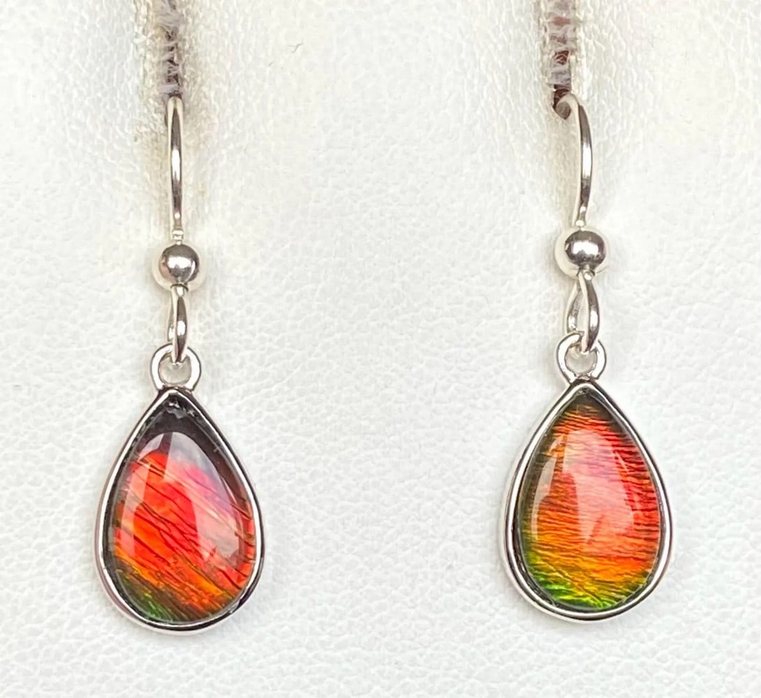 Reddish Orange Ammolite Earrings: Reddish Orange Ammolite Earrings These teardrop-shaped Ammolite earrings feature 12mm x 8mm low-dome quartz-capped triplets. Set in sterling silver with an anti-tarnish rhodium finish, they hang from
