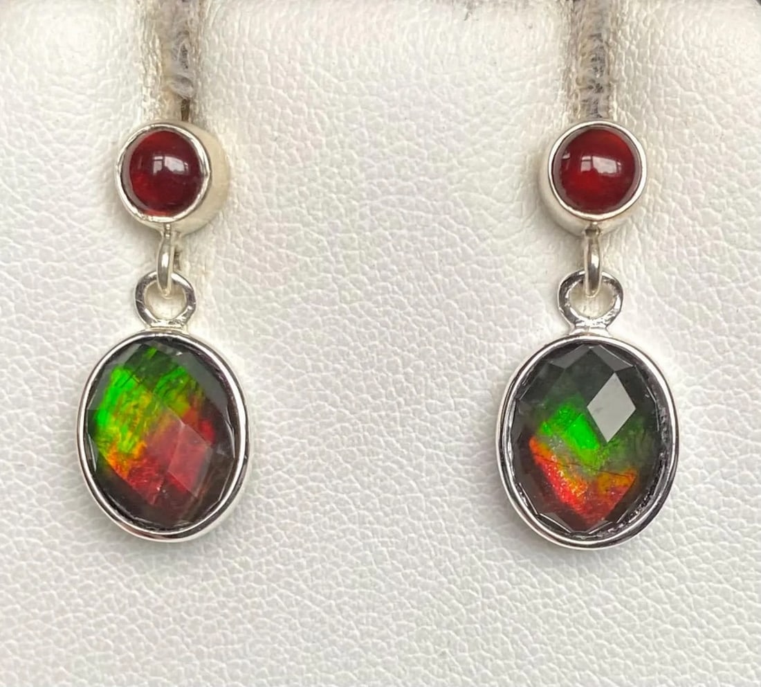 Maroon & Green Oval Cut Ammolite Earrings: Maroon &; Green Oval Cut Ammolite Earrings These Ammolite earrings display a striking blend of green and maroon, accented by deep garnet tones. The 10mm x 8mm faceted quartz-capped triplets are set