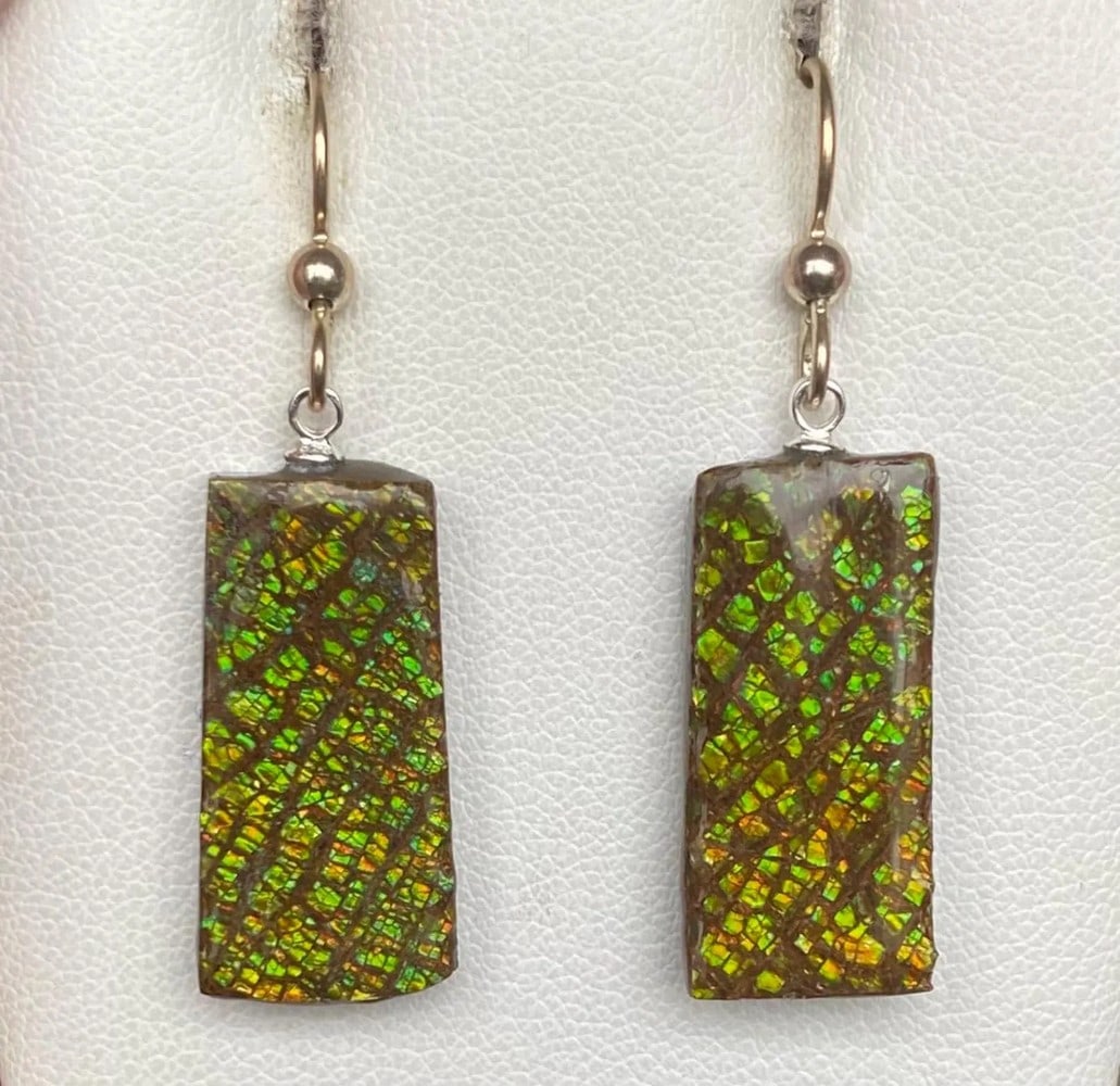 Green Dragon skin Ammolite Earrings: Green Dragon skin Ammolite Earrings This pair of earthy Ammolite earrings features gemstones averaging 23mm x 11mm with a delicate coating. Suspended from sterling silver pins and ear wires, they