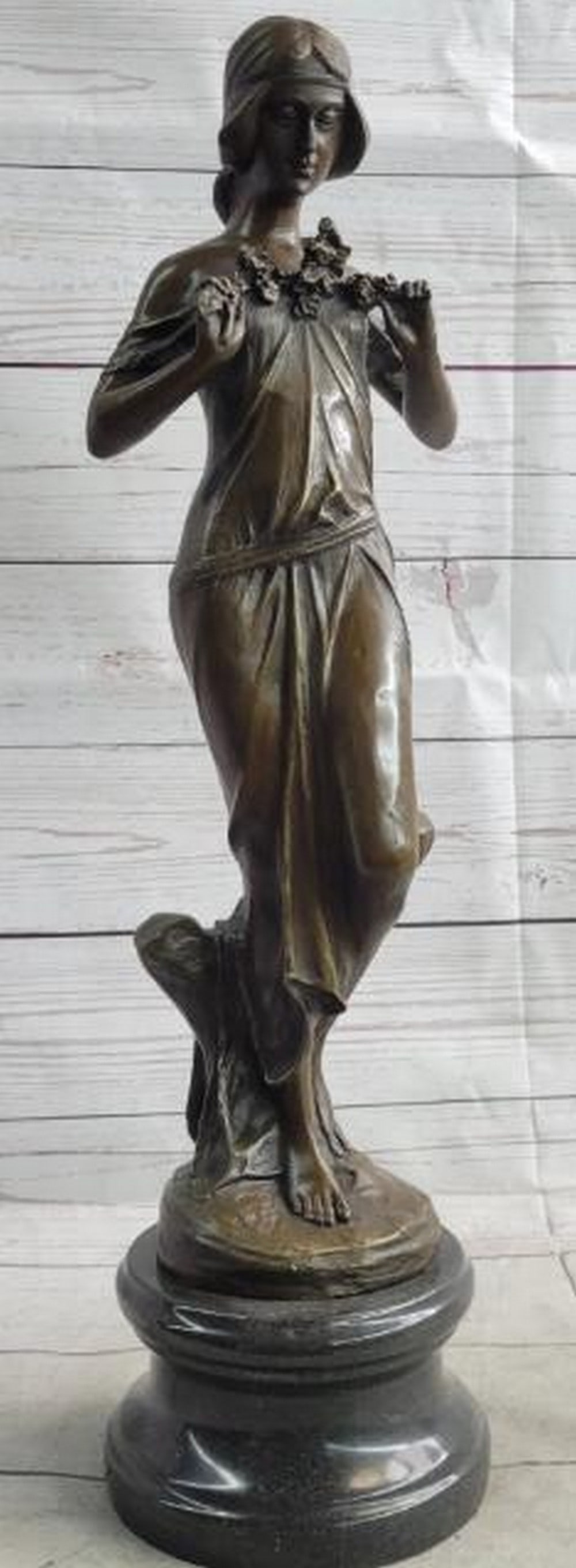 Embrace of Spring Bronze Sculpture - 19.5'' x 5.5'': Embrace of Spring Bronze Sculpture - 19.5" x 5.5". A bronze sculpture, inspired by and bearing the signature of renowned artist Jean Patoue, of a woman gently holding flowers to her chest, sym