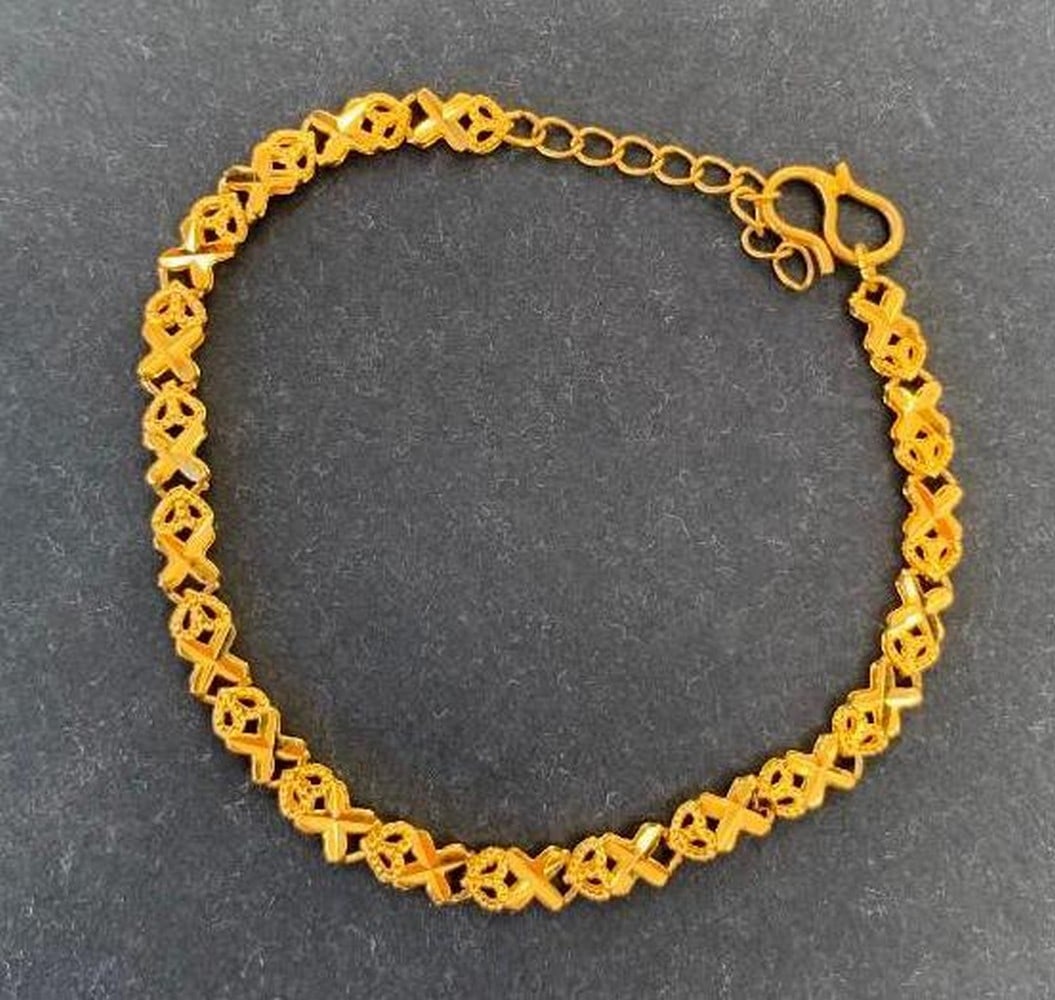 Gold Tone X and Heart Link Bracelet: Gold Tone X and Heart Link Bracelet A beautifully designed gold-toned bracelet showcasing a repeating pattern of X's and hearts, symbolizing love and connection. The linked design offers a smooth,
